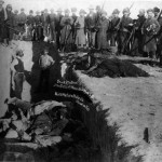 Burial of the dead after the massacre of Wounded Knee. U.S. Soldiers putting Indians in common grave; some corpses are frozen in different positions.